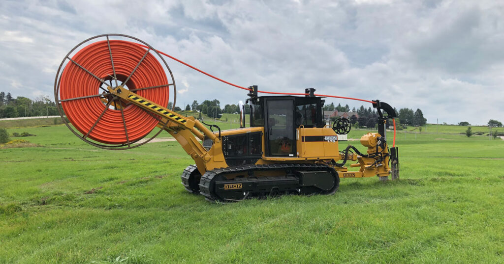 BRON 175 utility tractor equipped with a large orange cable drum reel in a green field, designed for heavy-duty underground cable laying.